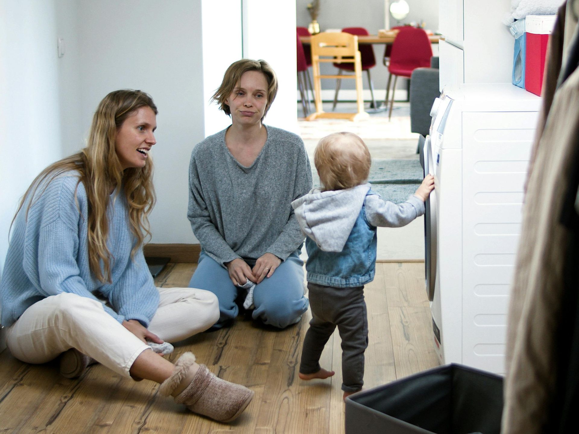 A mother and friend enjoy quality time with a toddler in a cozy home setting.