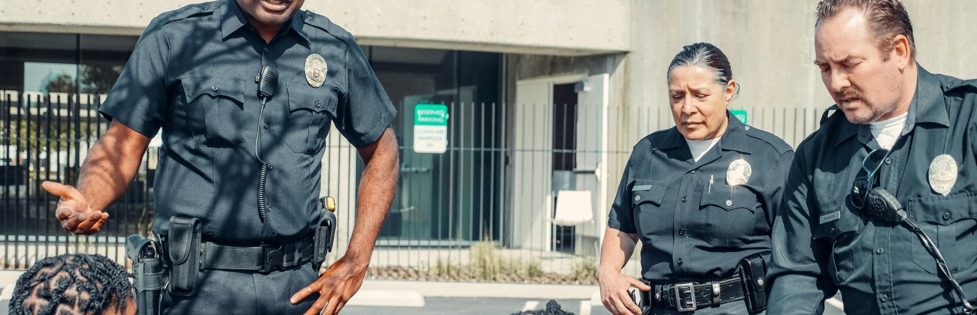 A group of police officers interact with civilians in a public outdoor setting.