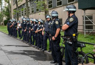 Police officers standing in line outside a building on a city sidewalk.